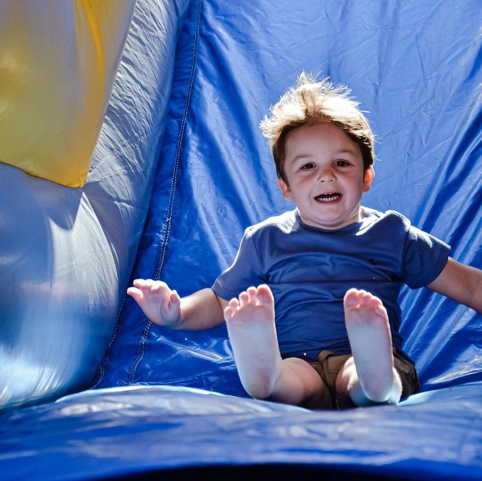 Child sitting on a blue inflatable slide