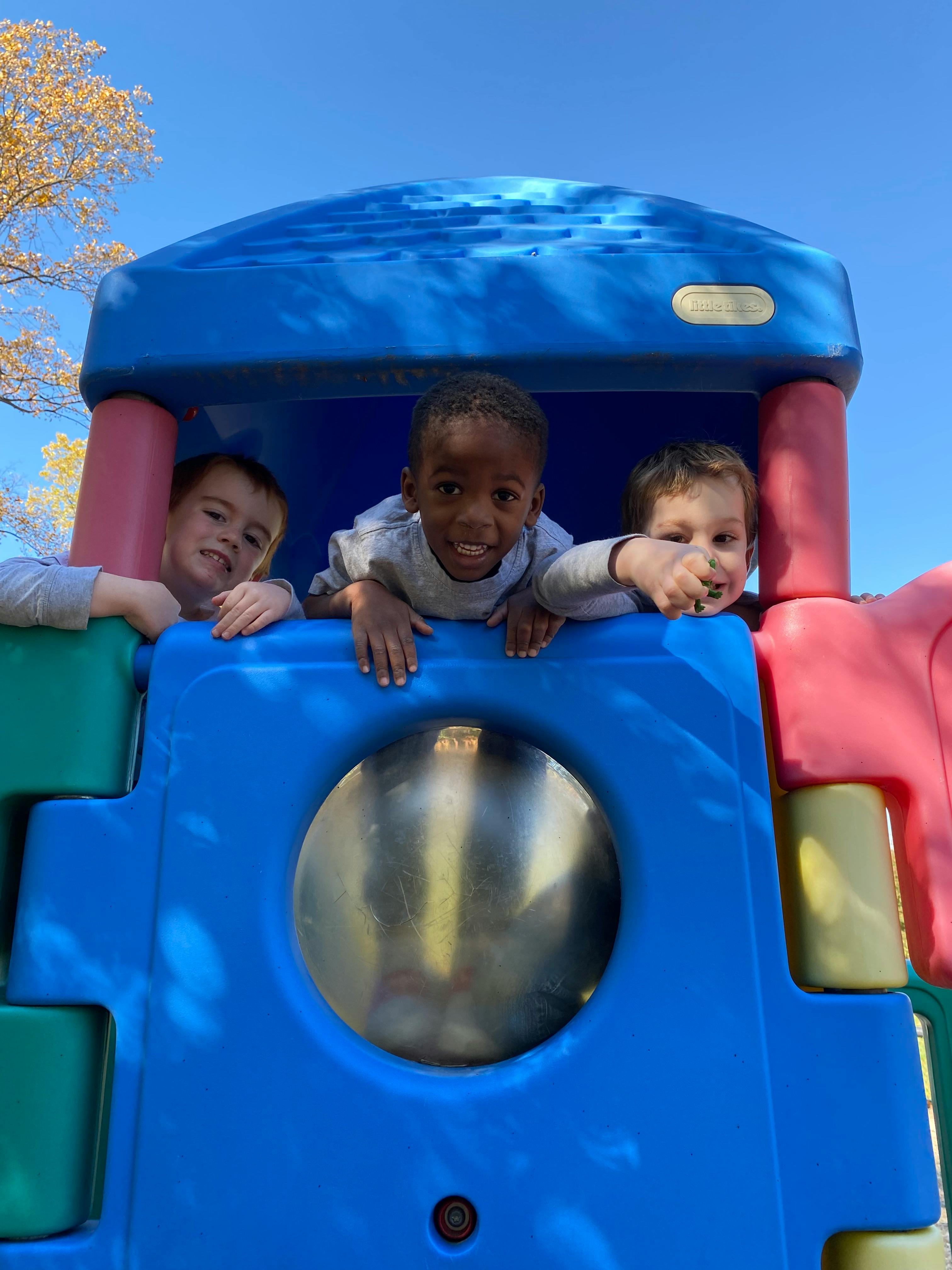 Three children looking out from a playground structure