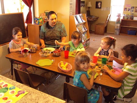 Adult and children sitting at a table with food