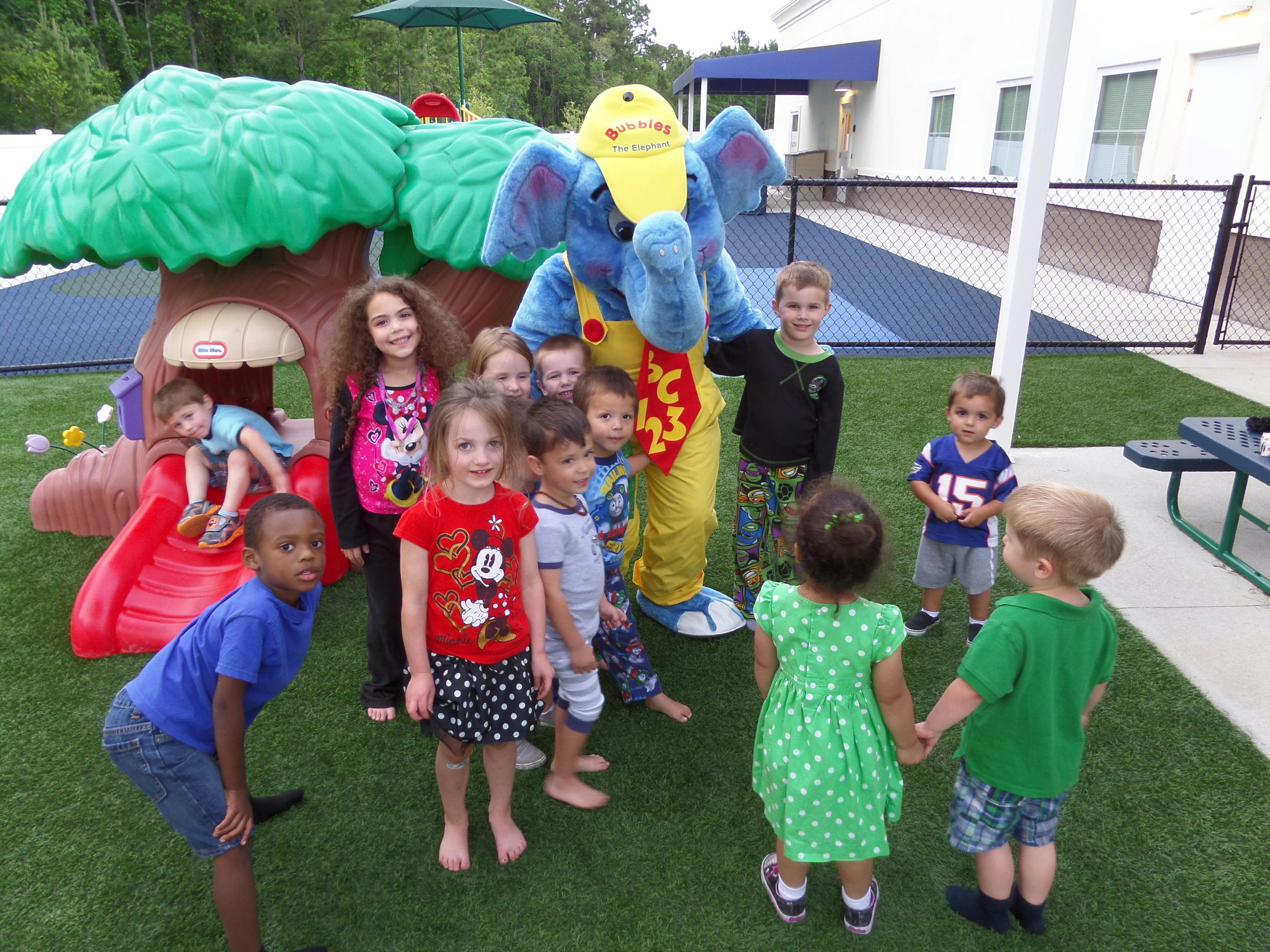 Children gathered around a person in an elephant costume on a playground