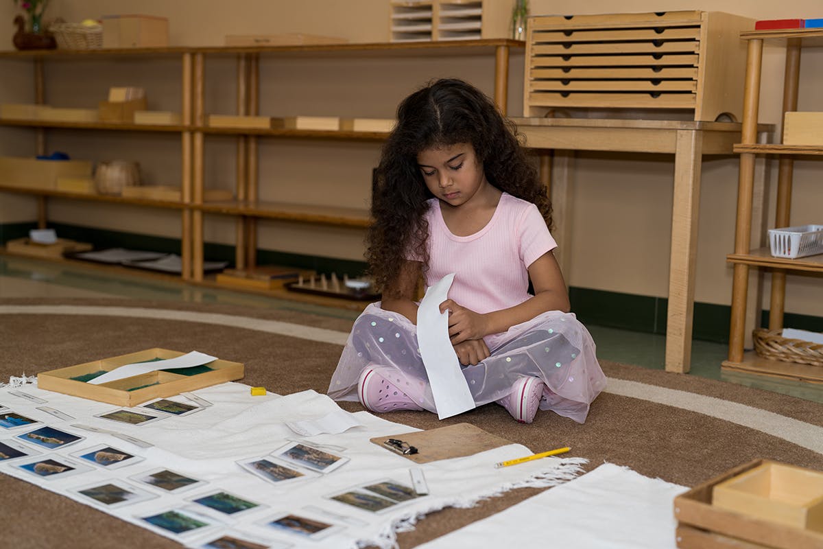 Child sitting on floor holding paper in a classroom