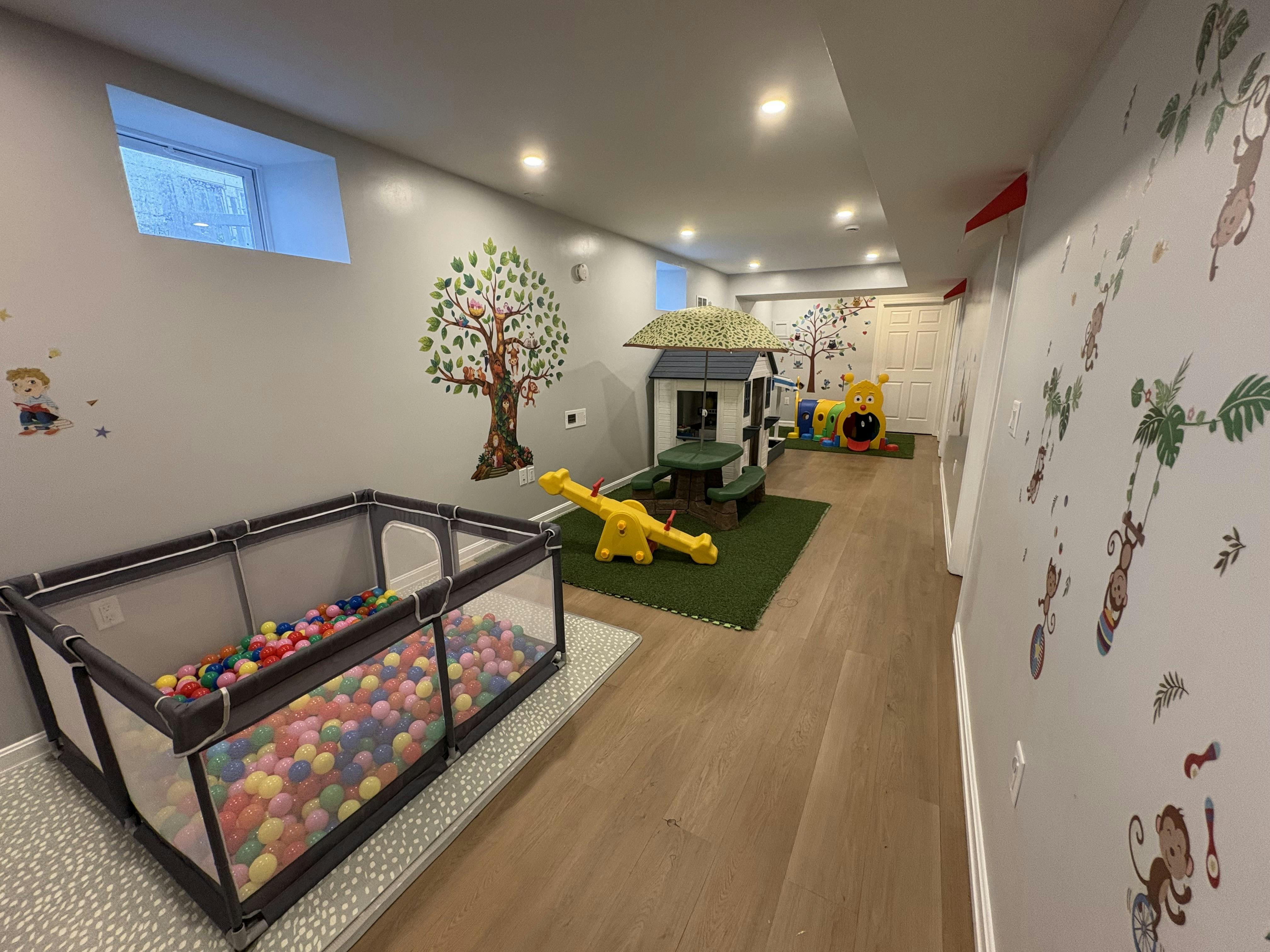 Indoor playroom with a ball pit, teeter-totter, and children play house