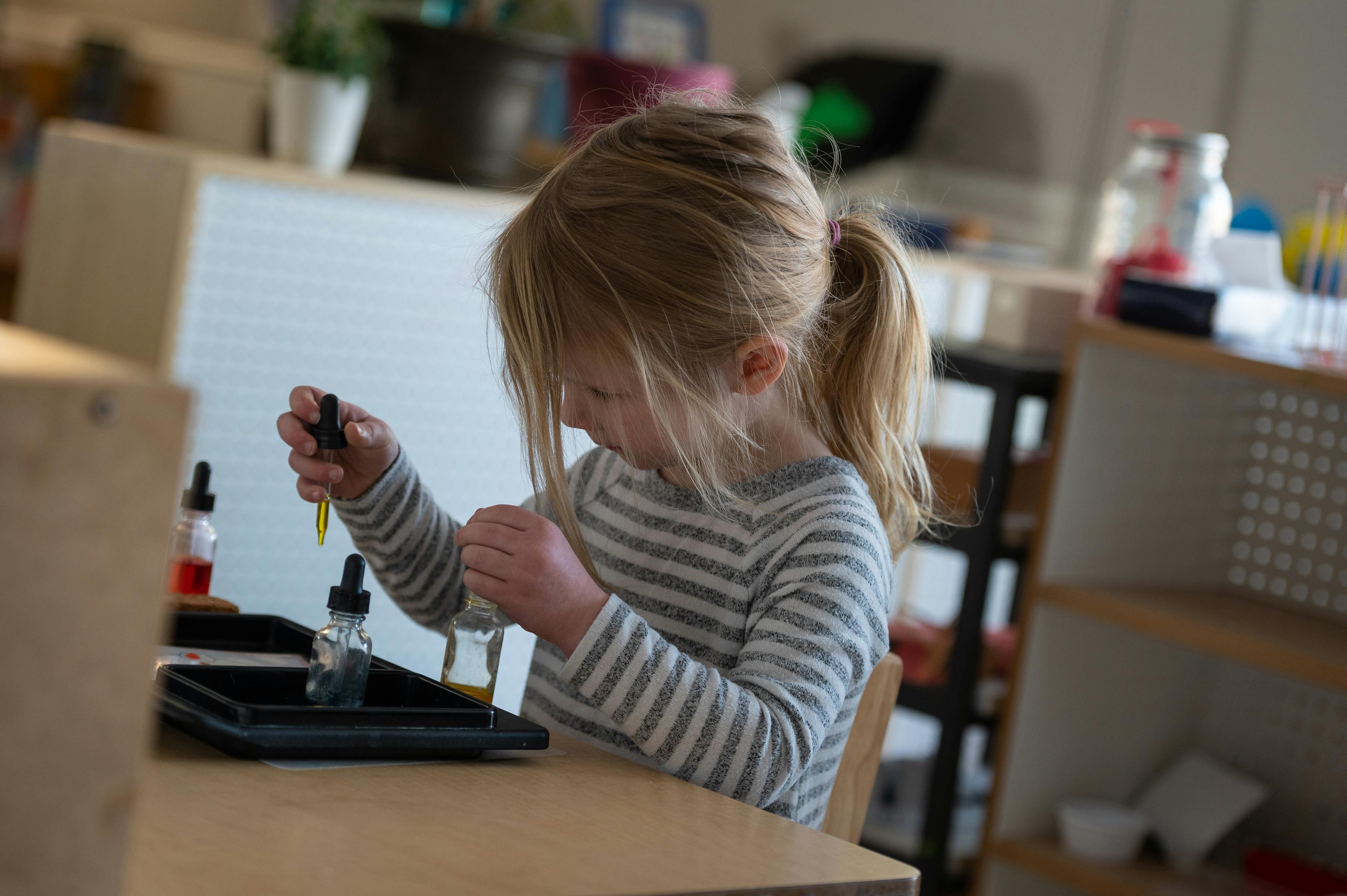 Child using a dropper with liquids at a table