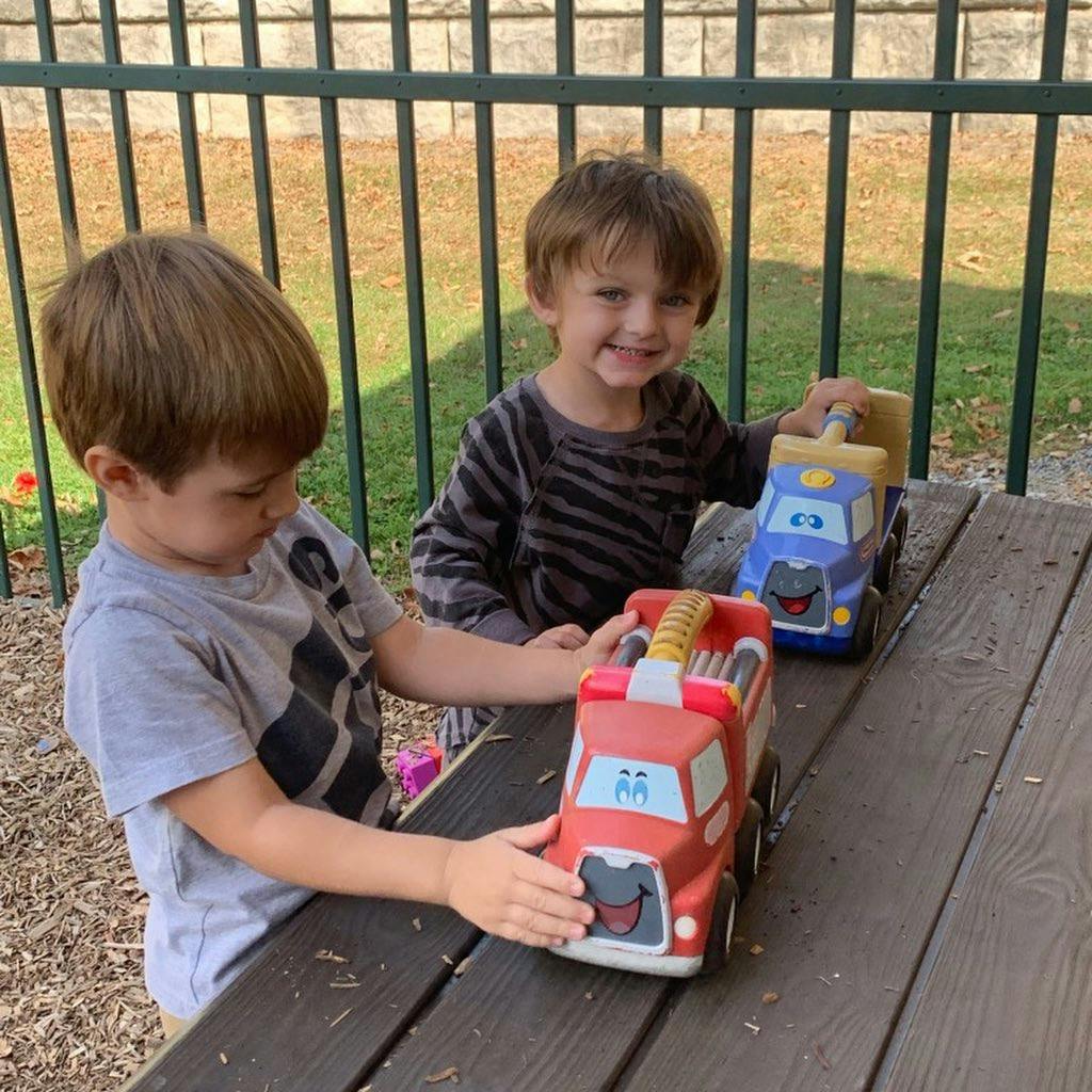 Two children playing with toy trucks on a wooden table