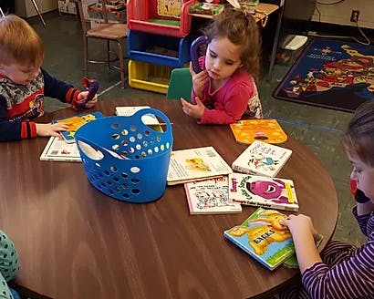 Three children sitting at a table with books