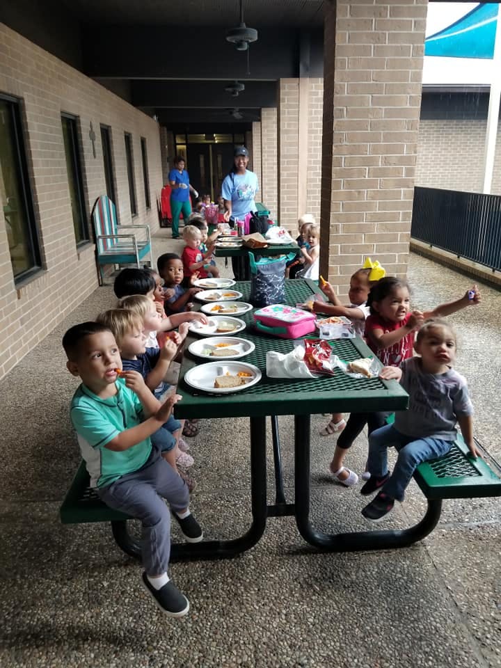 Children eating at picnic tables outdoors
