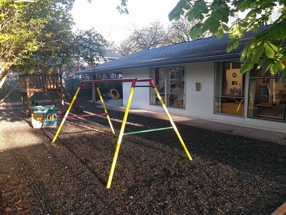Swing set on a playground with a building in the background