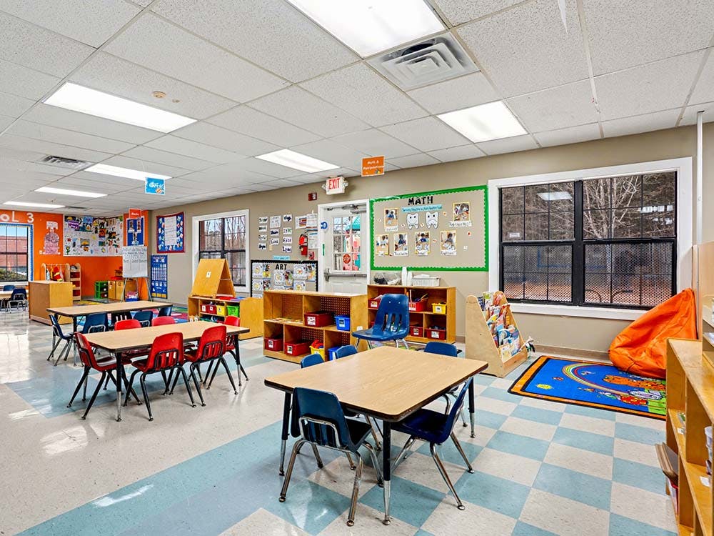 Empty classroom with small tables and chairs, shelves, and a math bulletin board
