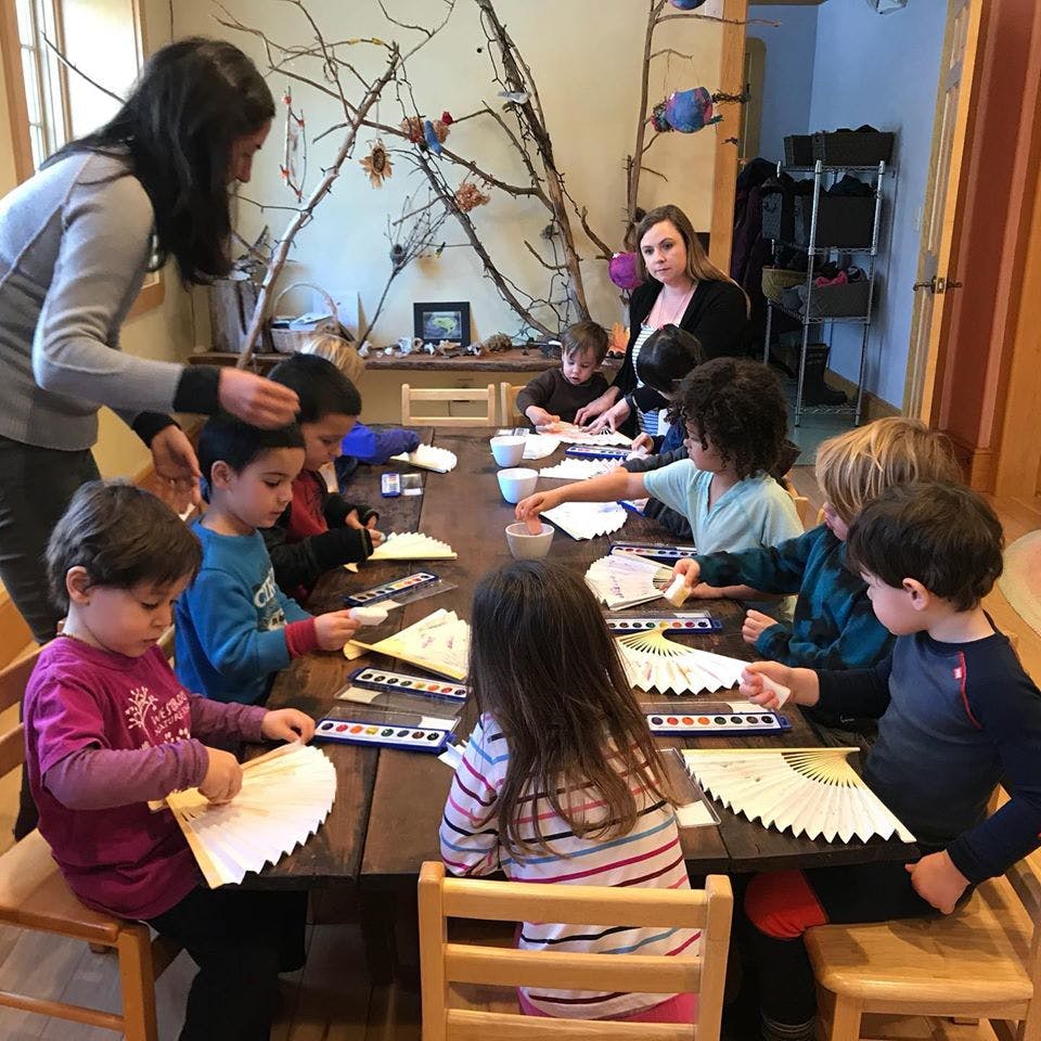 Adults and children sitting at a table doing crafts