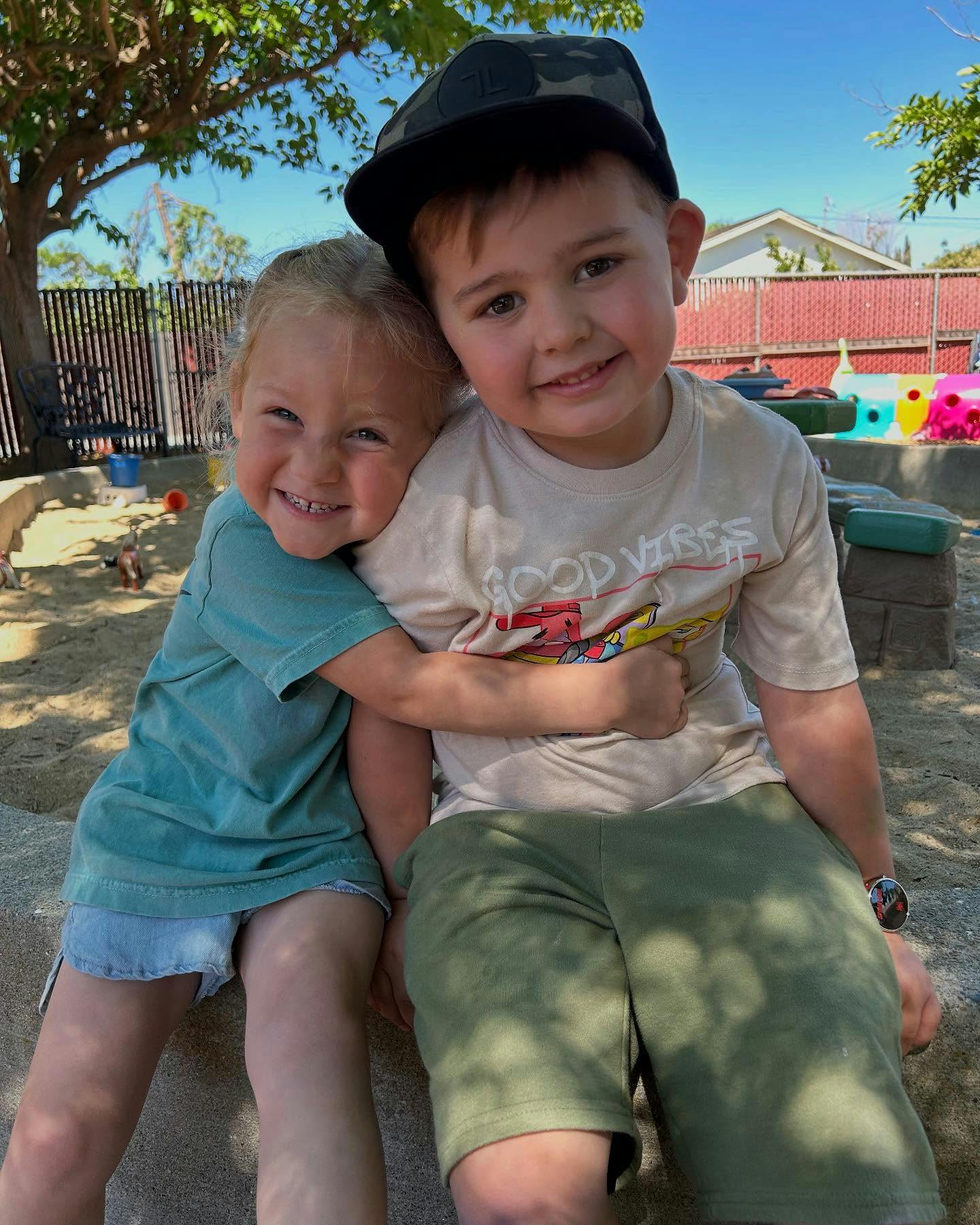 Two children sitting together, one with arm around the other