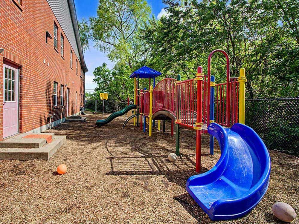 Playground with slides and climbing structures next to a brick building