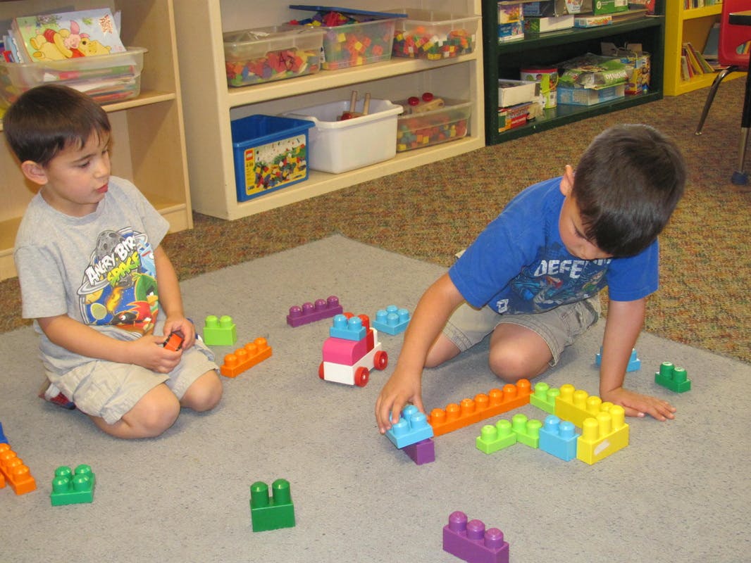 Two children playing with colorful building blocks on the floor