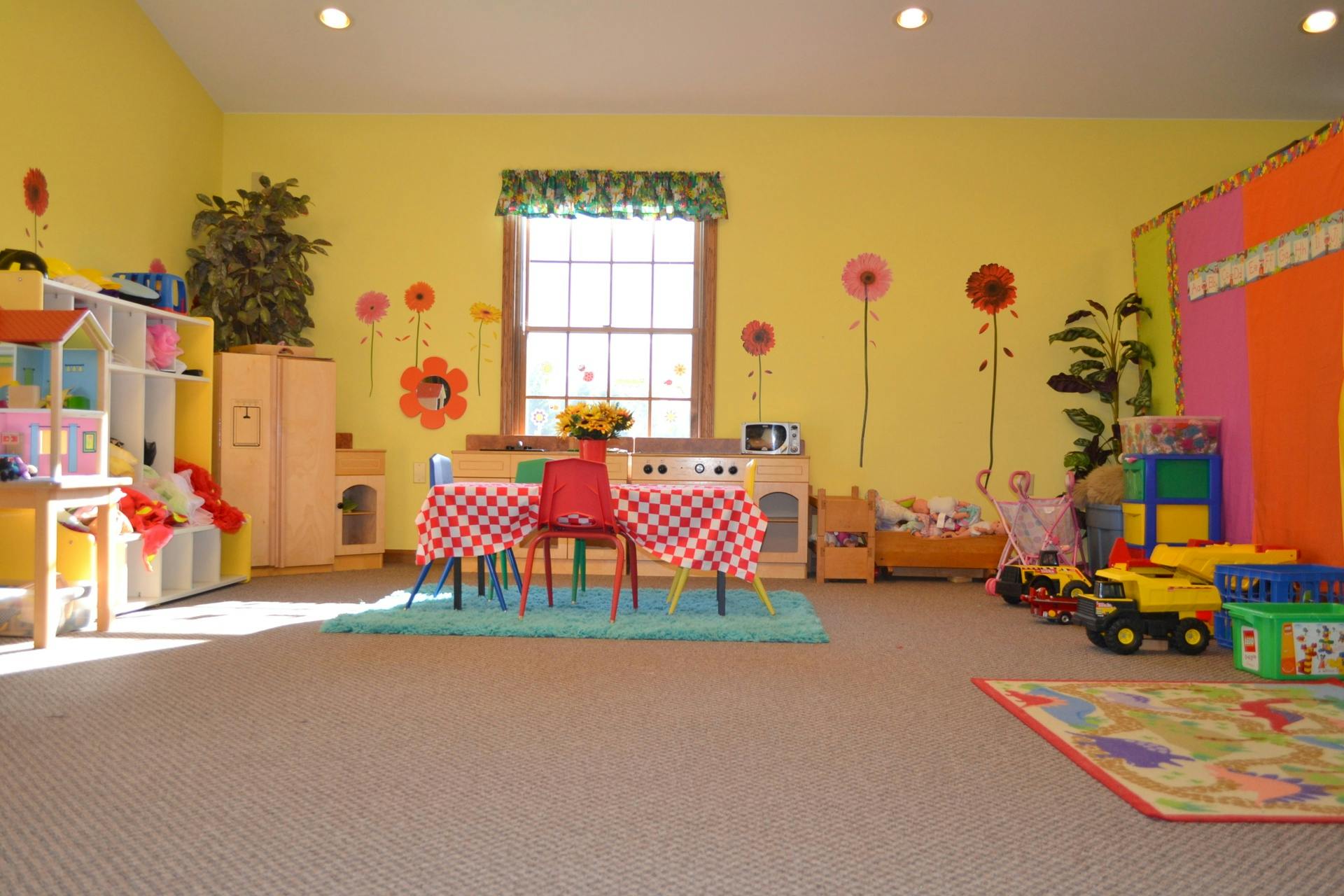 Playroom with small table and chairs, toys, and colorful wall decorations