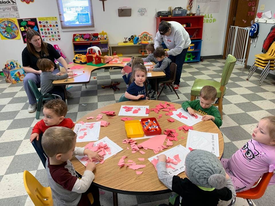 Adults and children doing crafts at tables in a classroom
