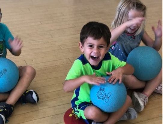 Children sitting on floor with blue balls