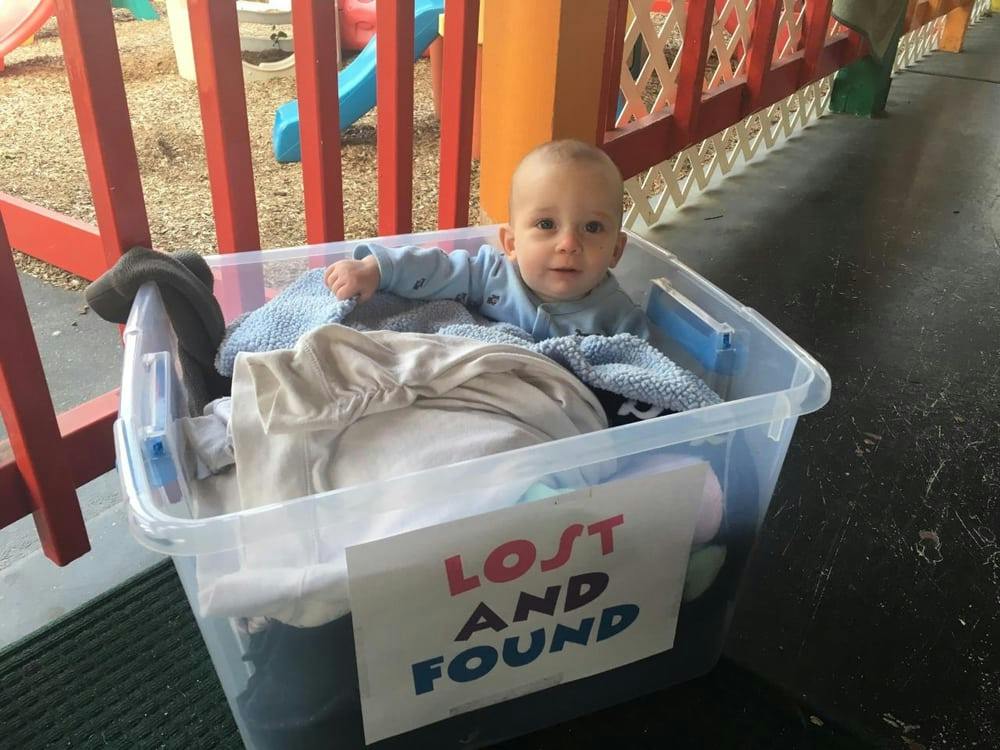 Child in a clear plastic bin with a "Lost and Found" sign