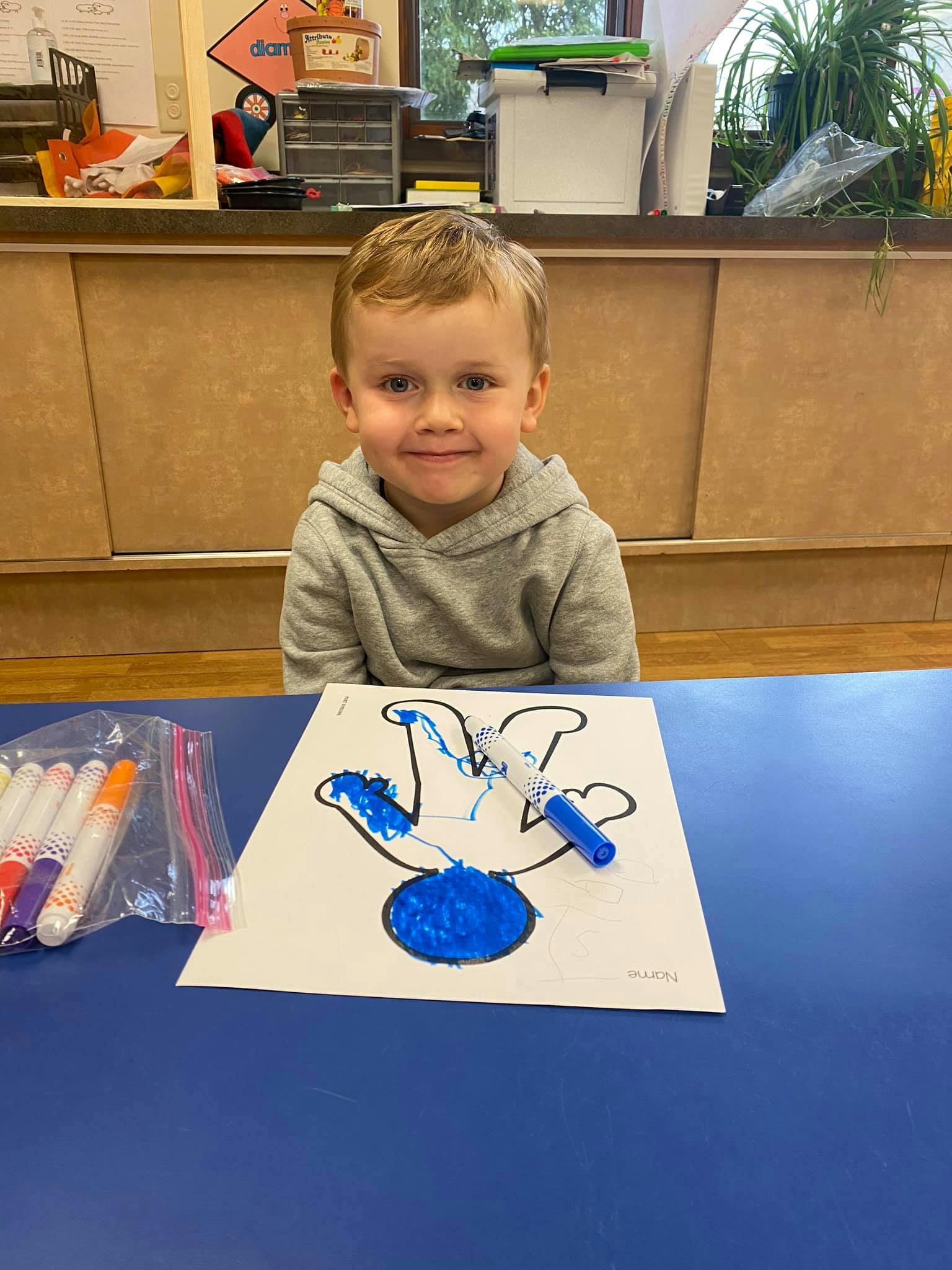 Child sitting at a table with a drawing of a handprint