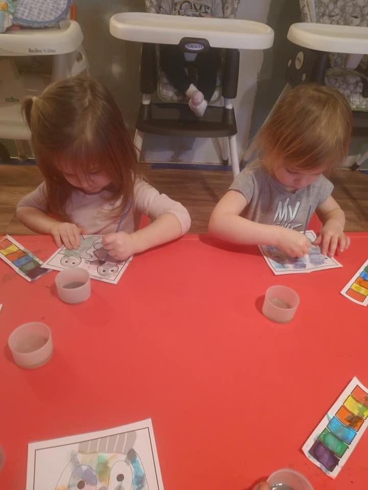 Two children painting at a red table