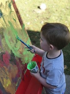Child painting on an easel outdoors