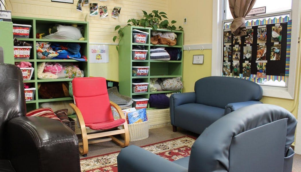 Room with green shelves, red chair, and blue couches