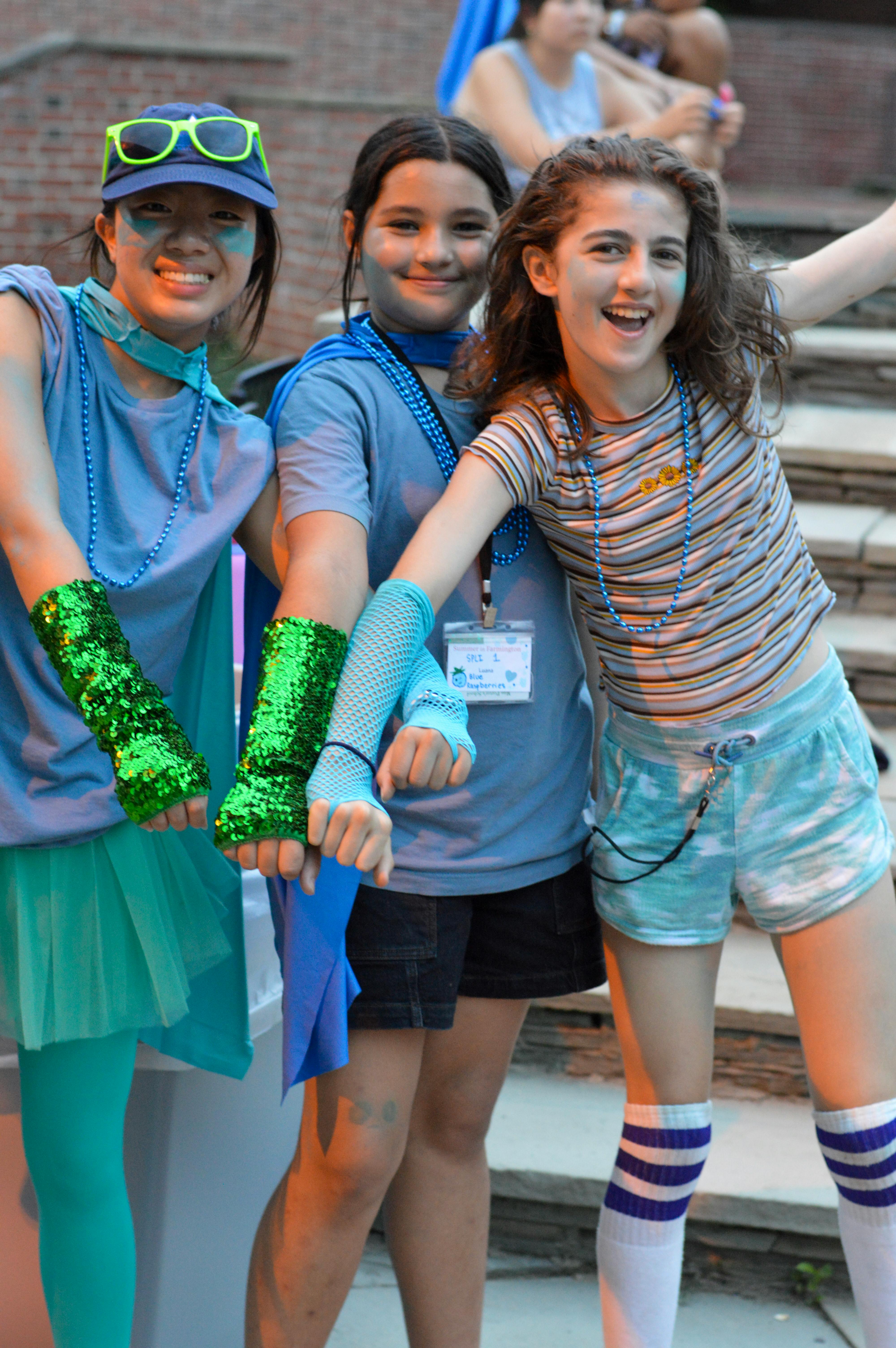 Three children posing together, one wearing green sequined arm warmers