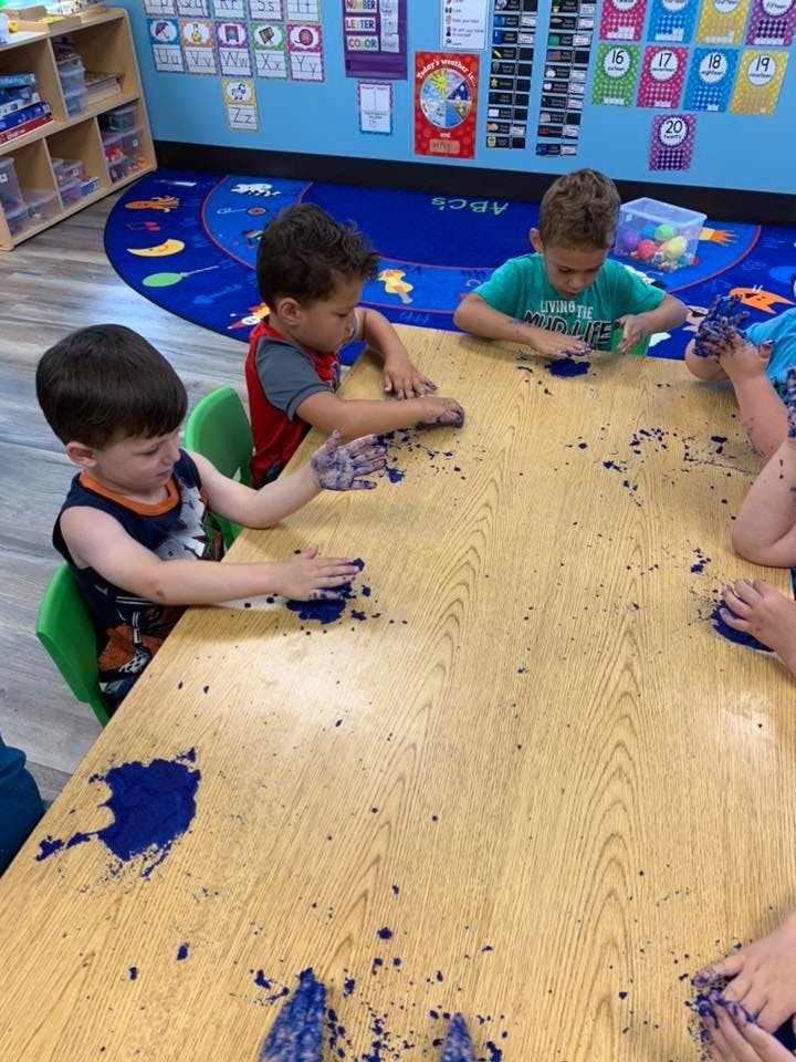 Children playing with blue kinetic sand at a table