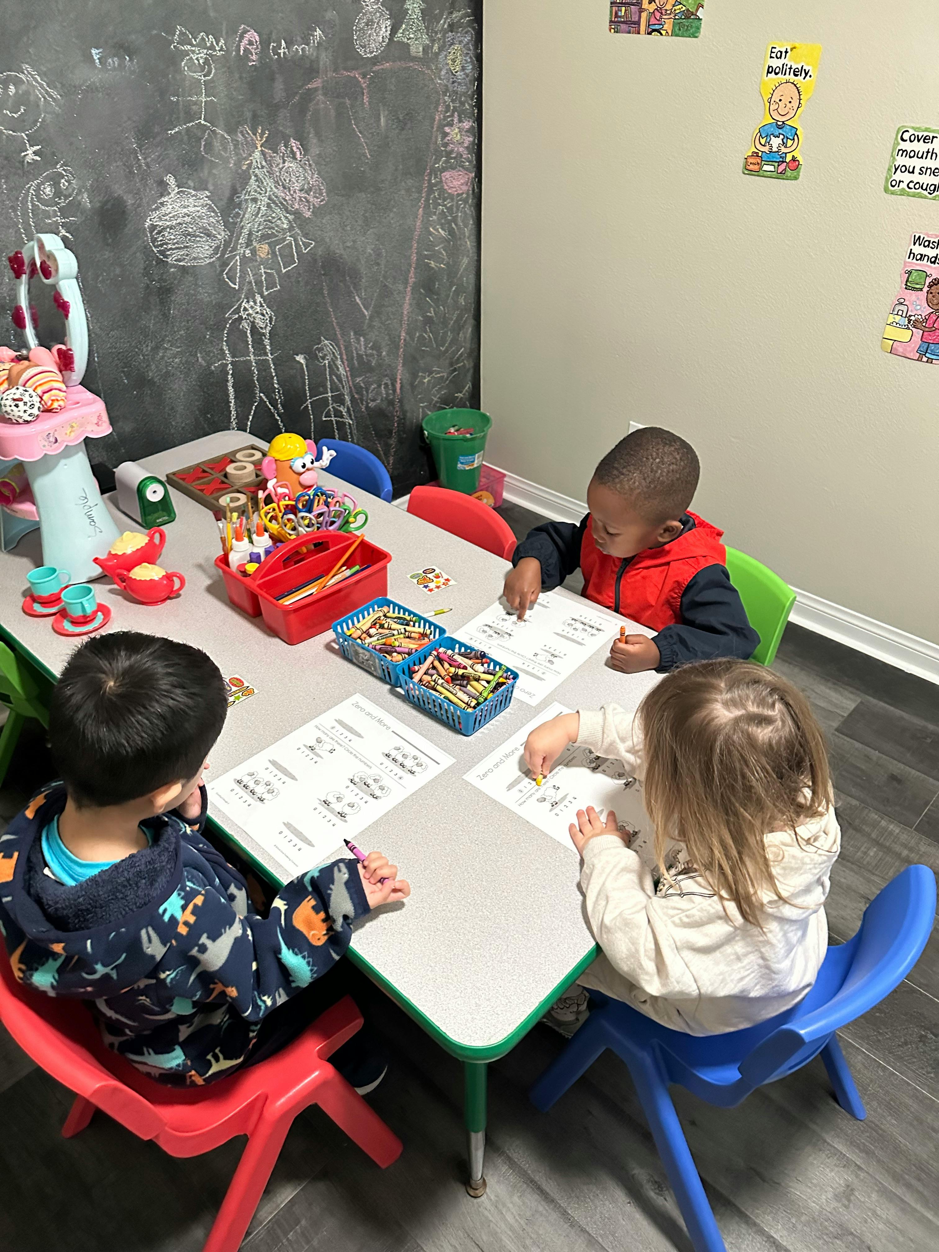 Three children sitting at a table doing schoolwork