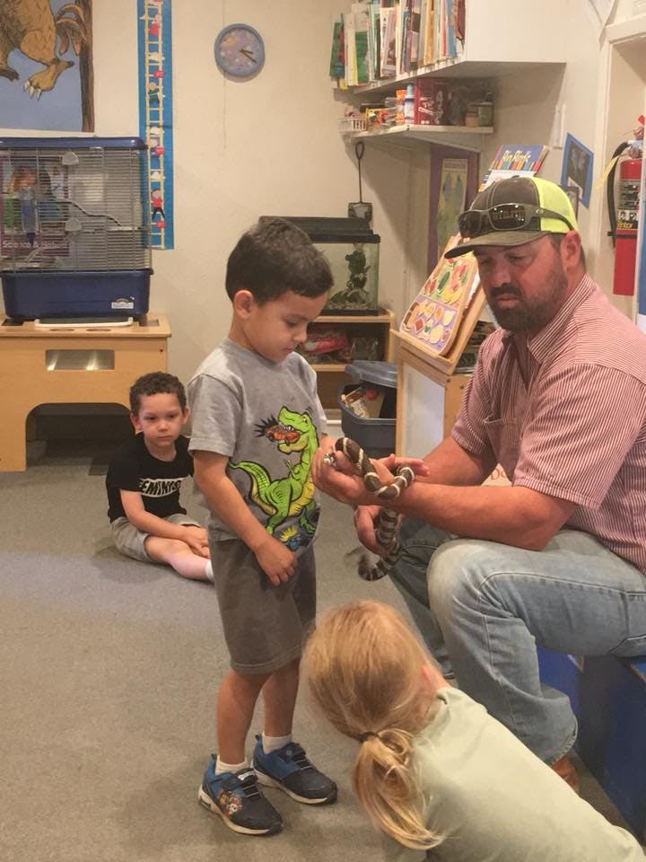 Adult holding a snake for children to observe