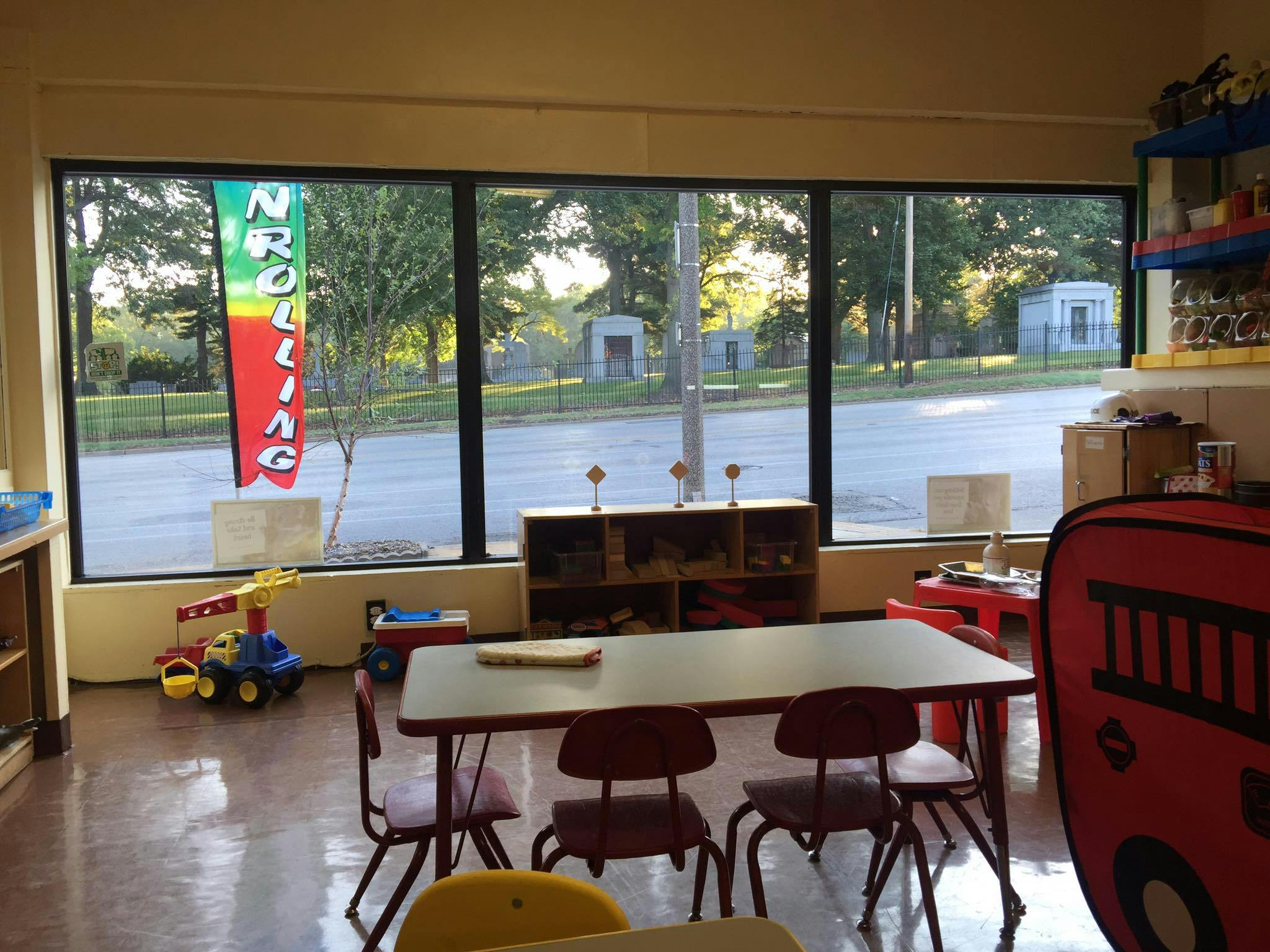 Classroom with small tables and chairs, toys, and a window looking outside