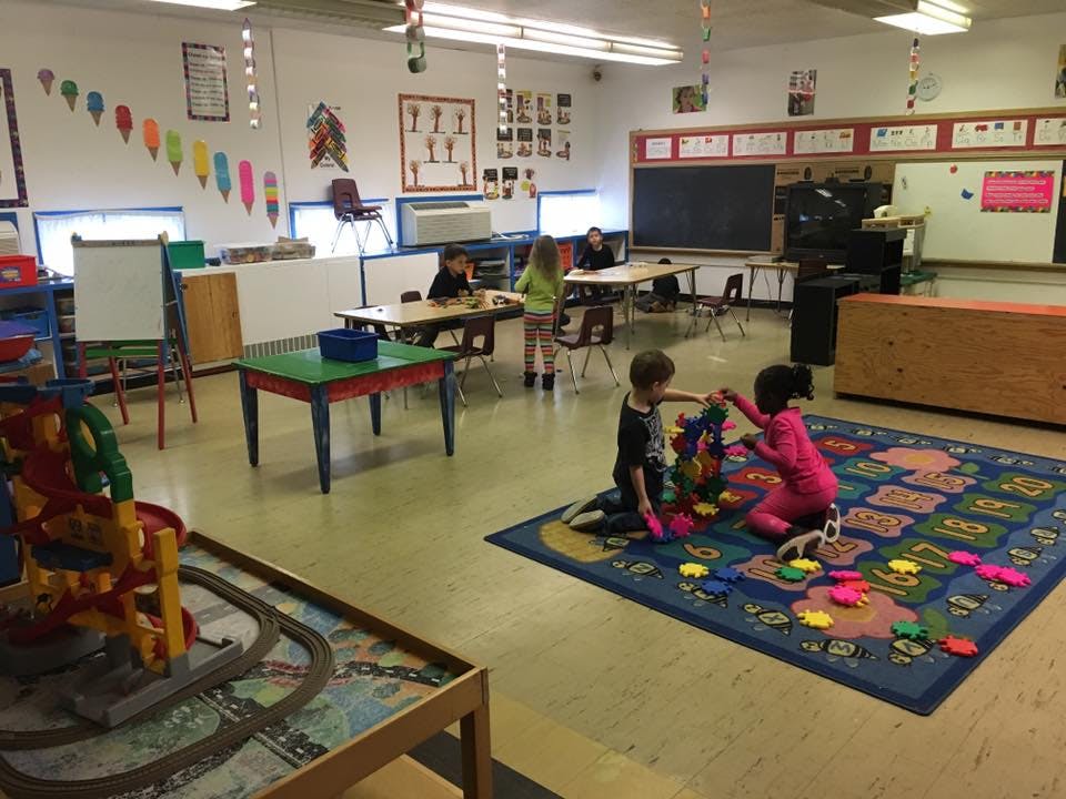 Children playing on a rug in a classroom