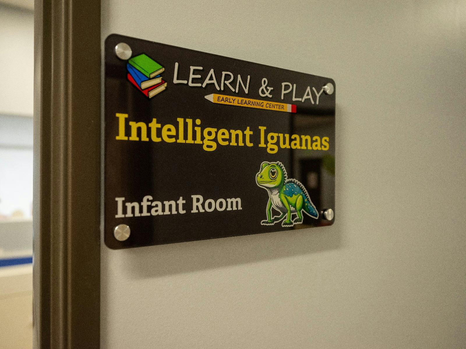 Sign for "Learn & Play Intelligent Iguanas Infant Room" with iguana illustration