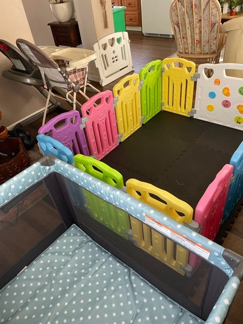 Playpen with colorful plastic fence panels and a crib