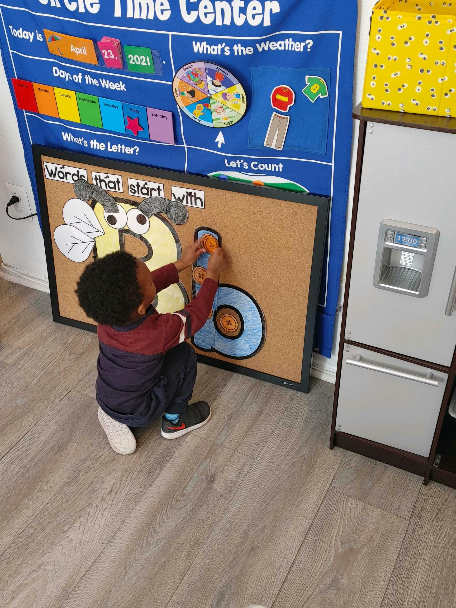 Child playing with a large letter B on a cork board