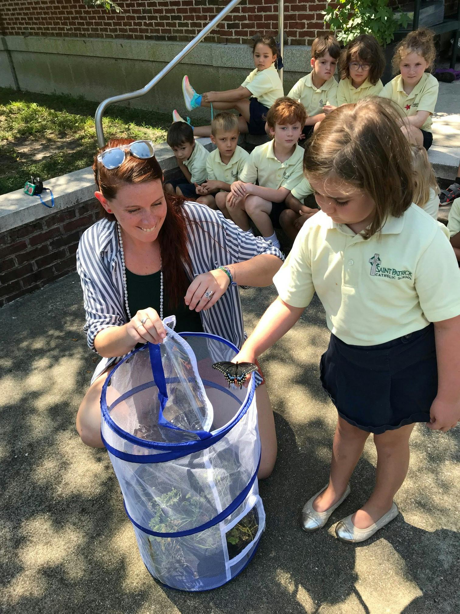 Adult and child releasing a butterfly from a mesh container