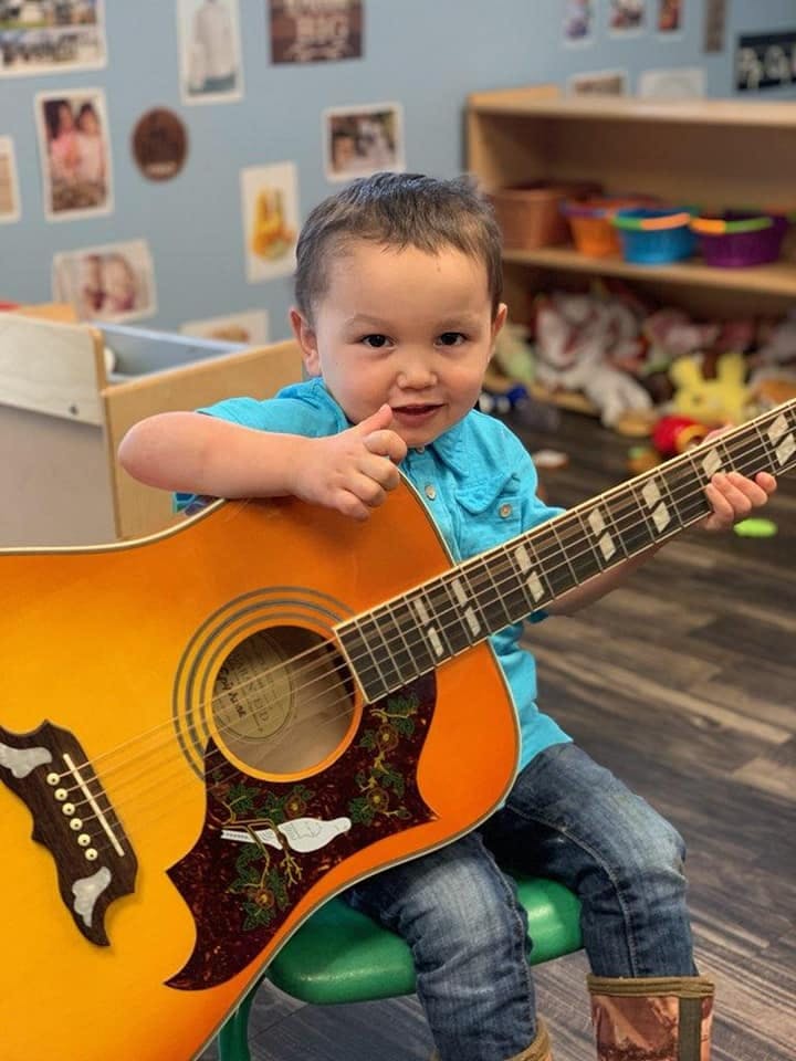 Child sitting and holding an acoustic guitar