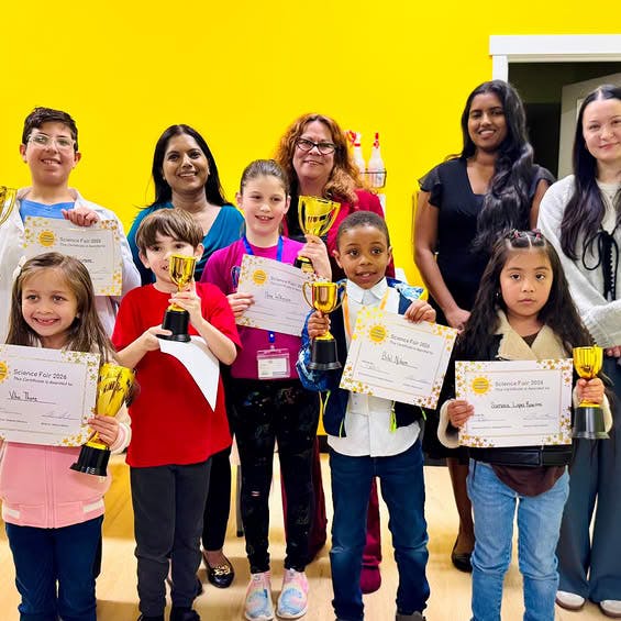 Adults and children holding certificates and trophies
