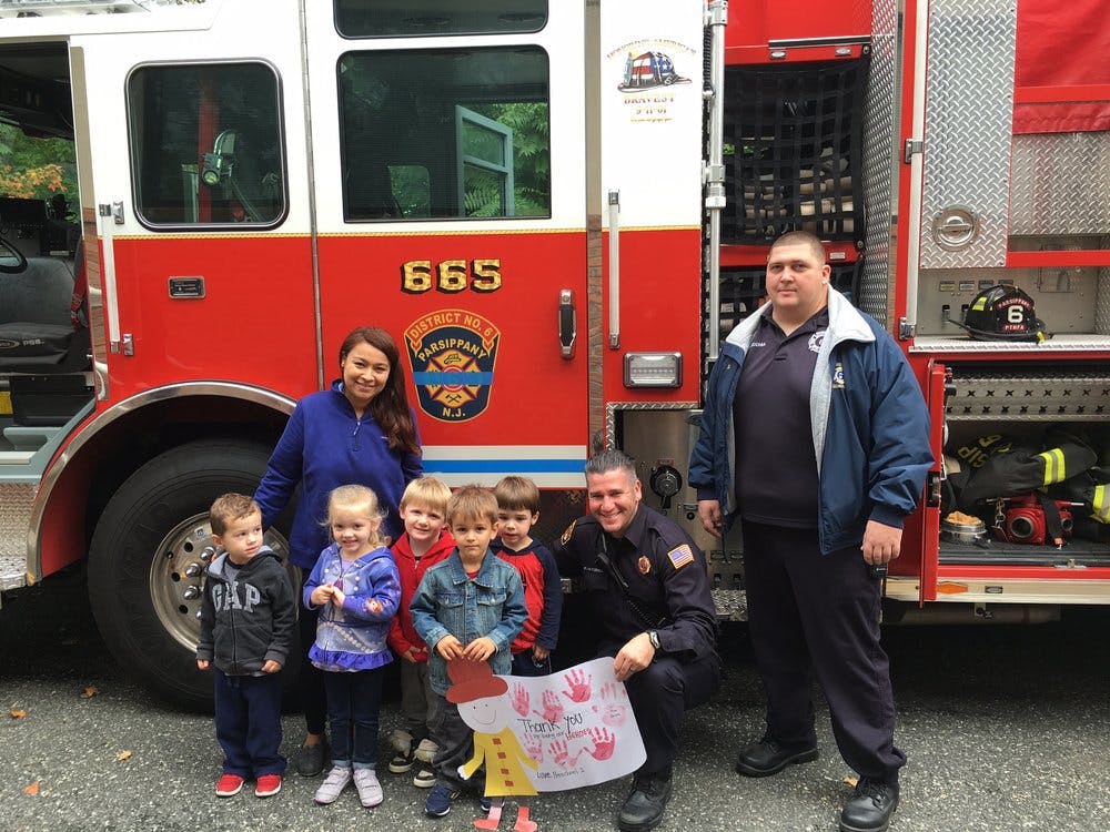 Adults and children posing in front of a fire truck