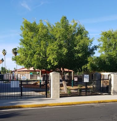 Fenced outdoor area with trees and a red canopy