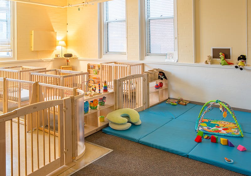 Nursery room with multiple cribs and a play area with blue mats