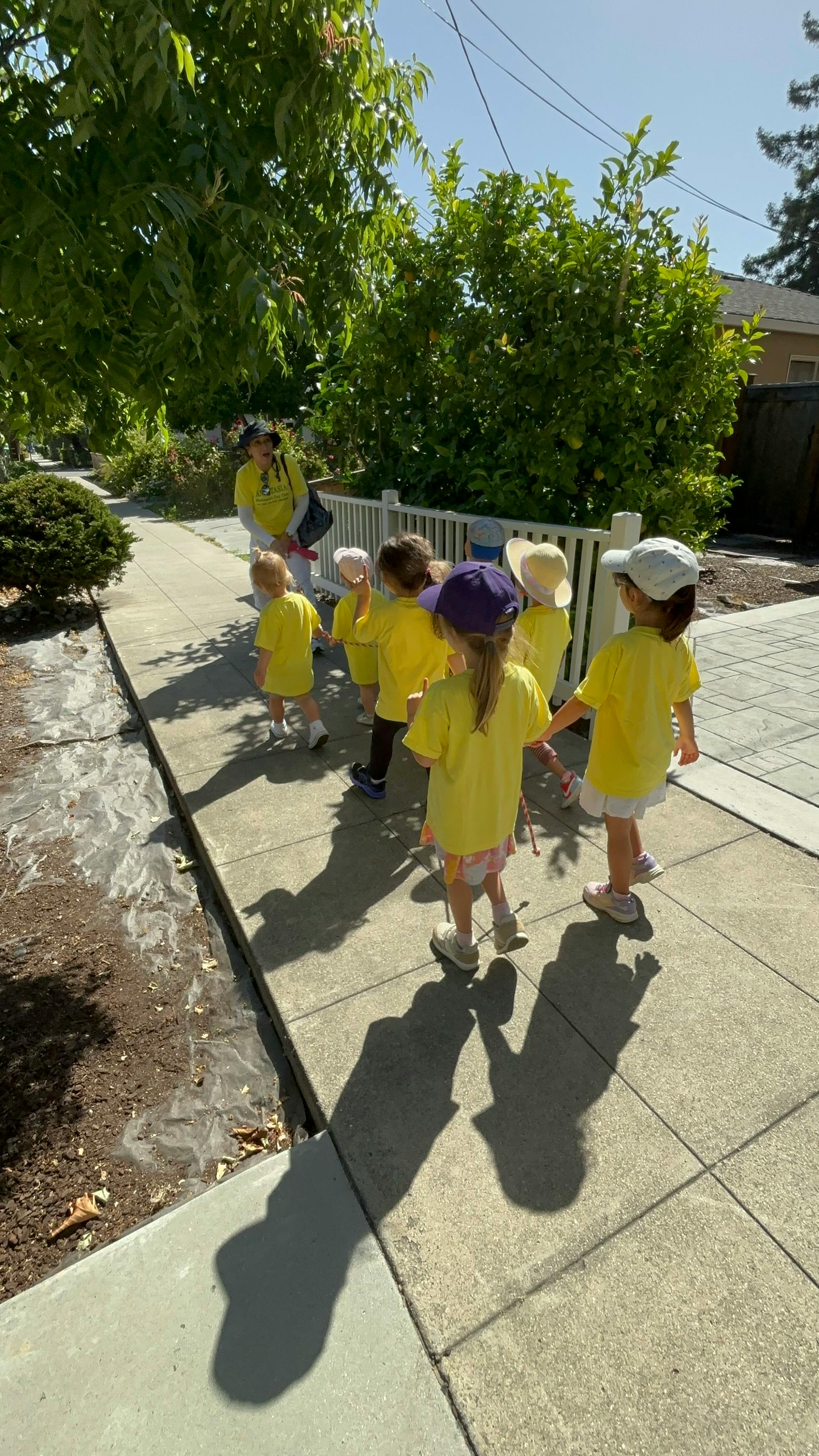 Adult and group of children walking on a sidewalk