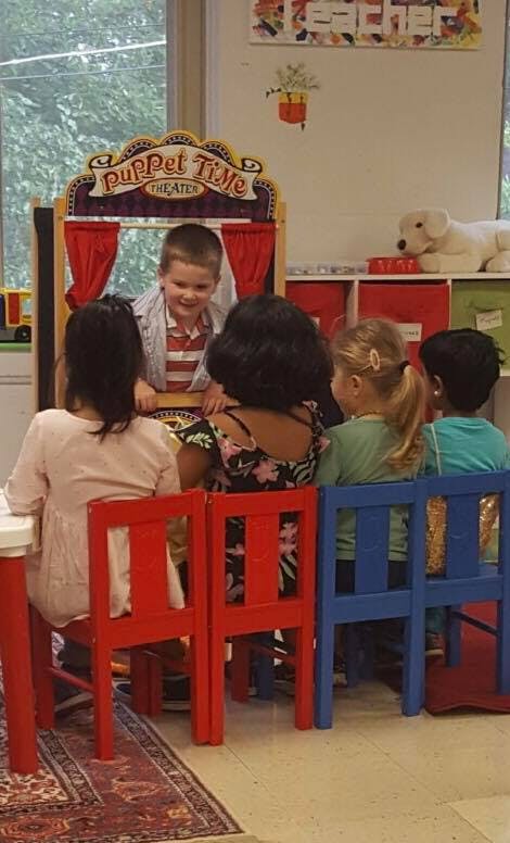 Child performing a puppet show for other children in a classroom