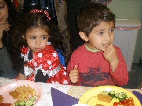 Two children sitting at a table with plates of food