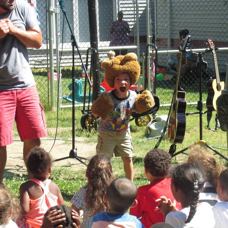 Child in a furry hat and gloves performing for other children