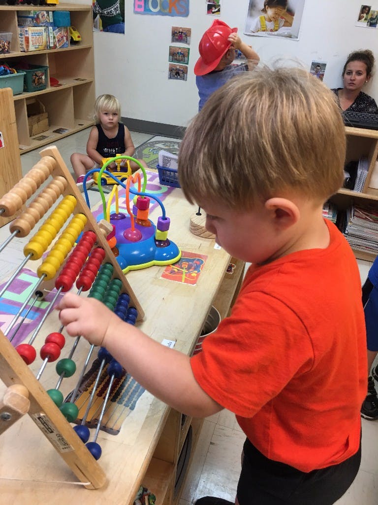 Child playing with an abacus in a classroom