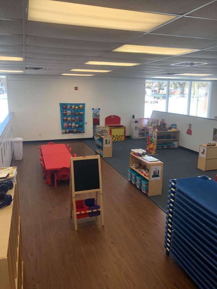 Empty classroom with small tables, chairs, and shelves