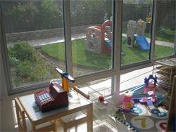 Indoor play area with toys and outdoor playground visible through window