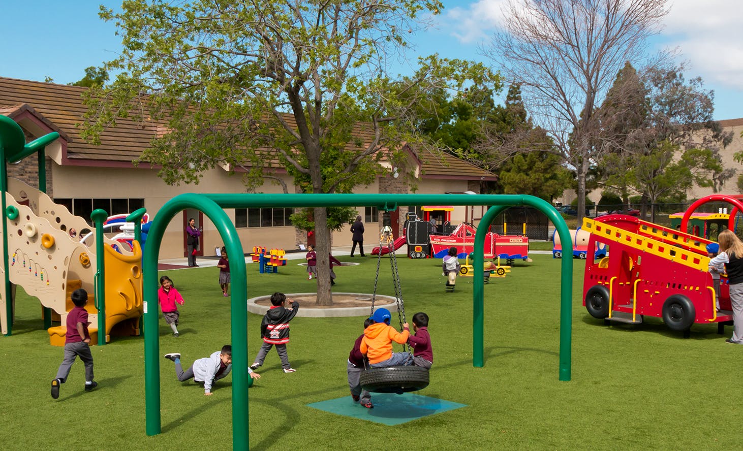 Children playing on a playground with swings and climbing structures