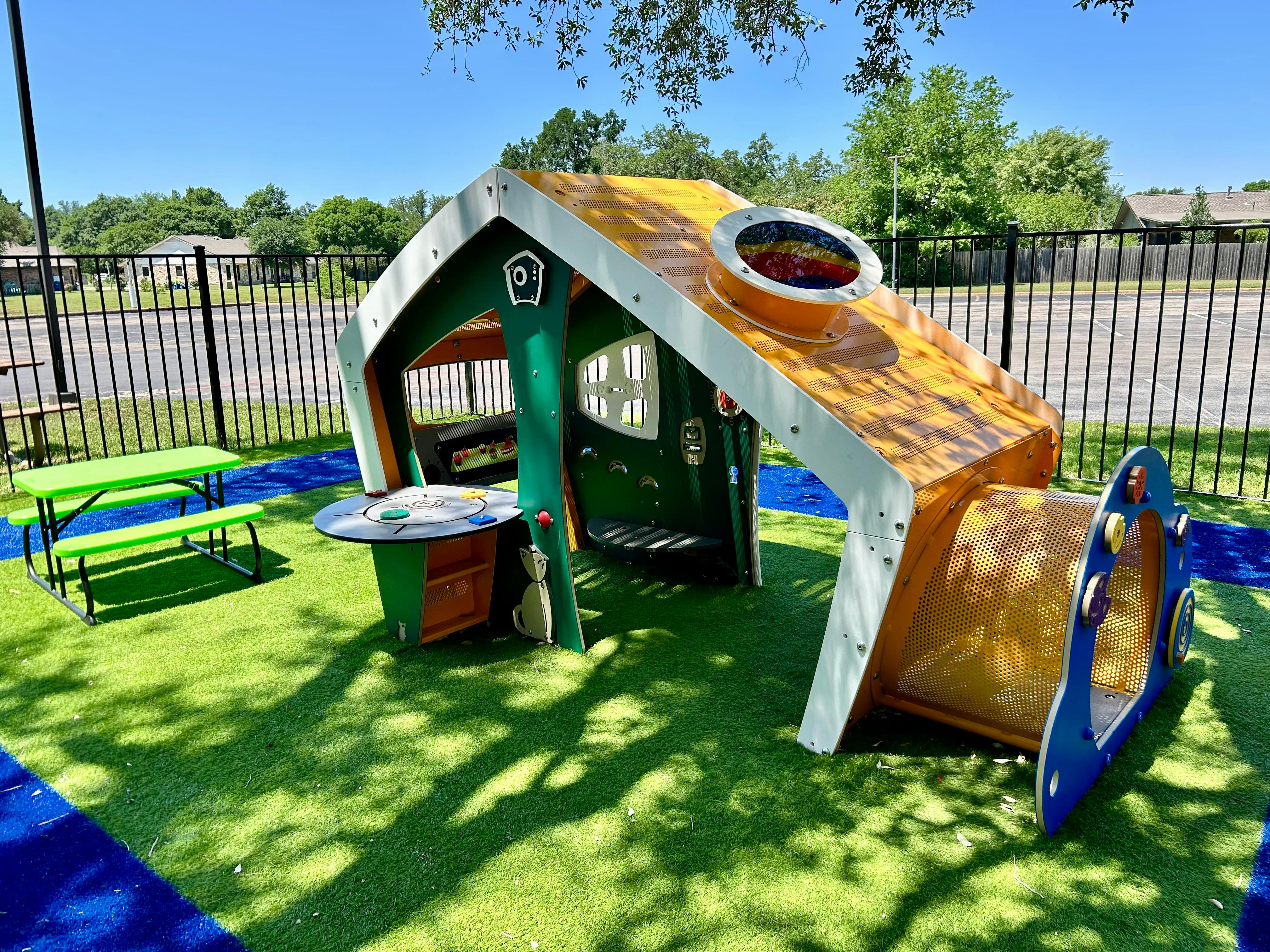 Playground with a playhouse and slide on artificial turf