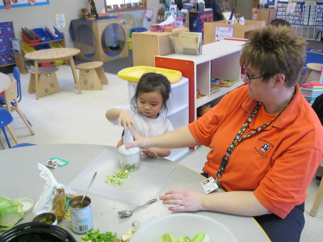 Adult and child preparing food in a classroom