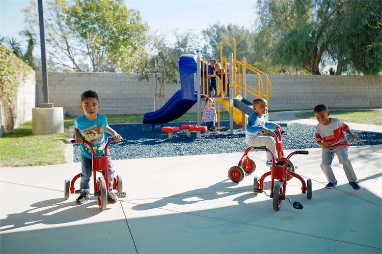 Children playing on tricycles and a playground
